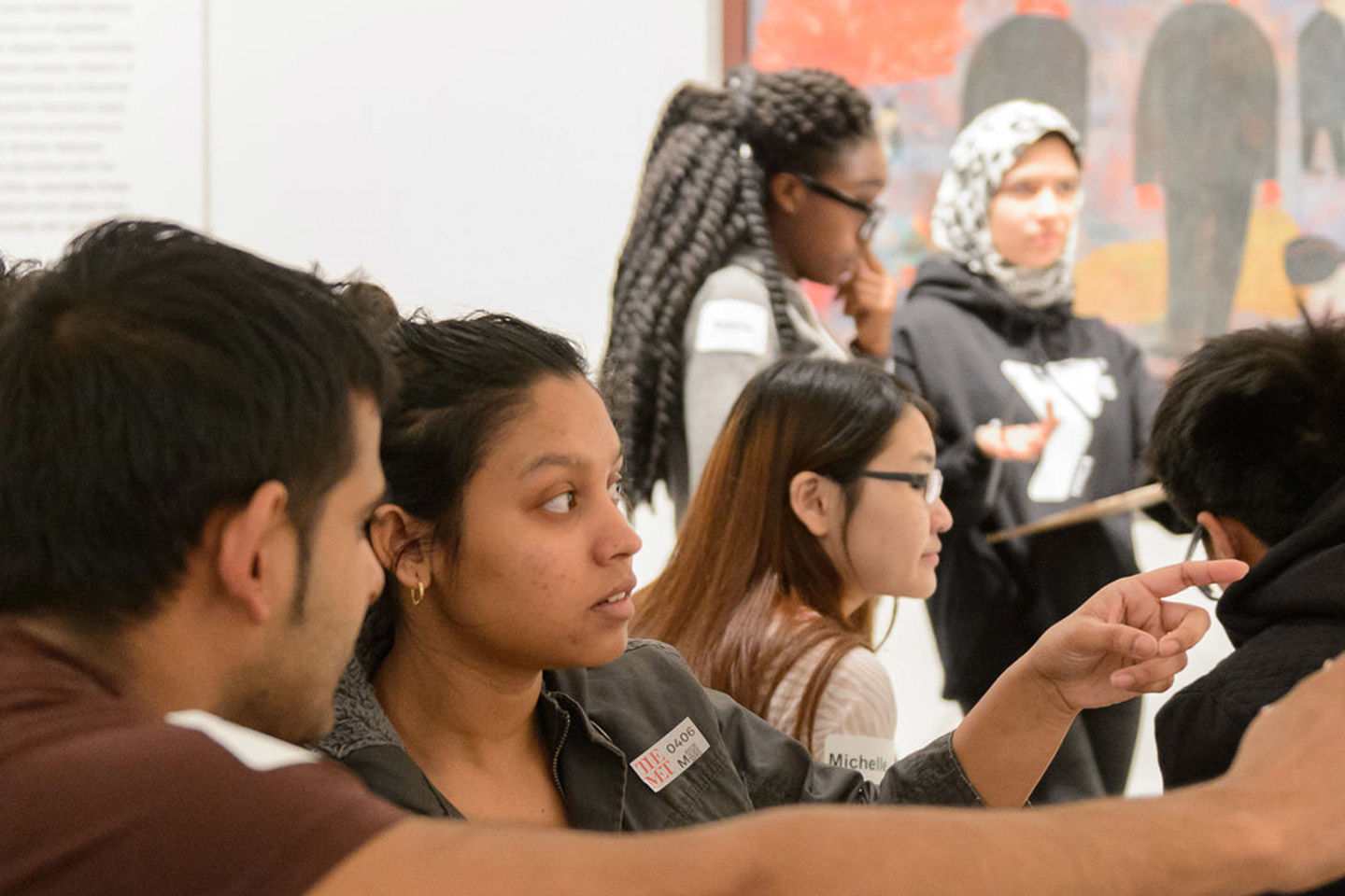 A group of young adults are studying and pointing to an object off camera